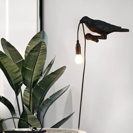 Raven wall light on a white wall next to a house plant