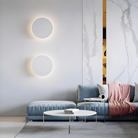 Two round, tactile wall lights with 3-color option hung in a designer living room above a gray sofa