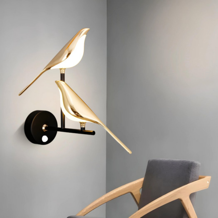 Wall light with two golden magpies and motion detector functionality hanging in a gray room next to an armchair