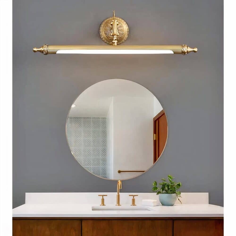 above a mirror in a bathroom is a bronze art deco wall light