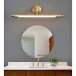 above a mirror in a bathroom is a bronze art deco wall light