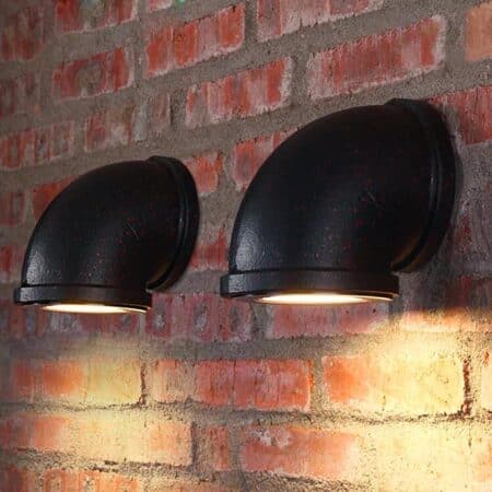 on a red brick wall are two black industrial spot wall lights