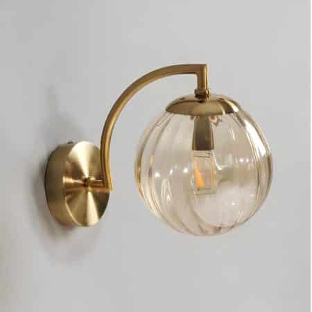 Vintage-style wall sconce with gold frame and smoked glass ball with vertical stripes. The wall light is mounted on a gray wall.
