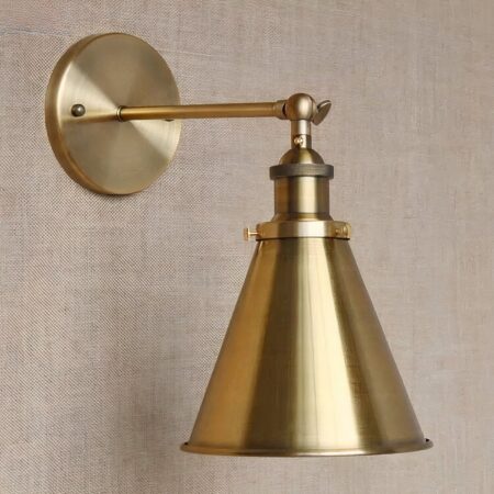 on a light brown wall, a gilded metal wall light in industrial style
