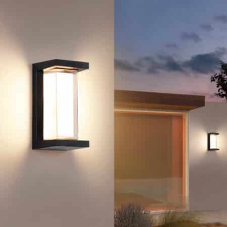 Rectangular wall light with black structure on the ends and acrylic in the center for lighting. Mounted on a white exterior wall. To the right, in the distance, a wall with the same wall light on, and a bay window to its left.