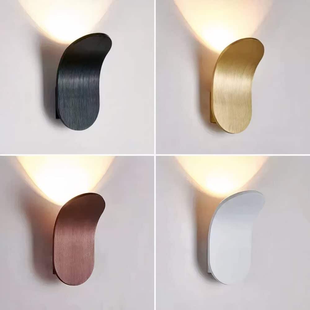 photo divided into 4 with the same modern oval aluminum wall sconce curved upwards lit. Top left is black, top right is gold, bottom left is brown and bottom right is white.