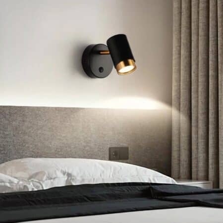 a modern black wall light is seen above a headboard in a gray bedroom