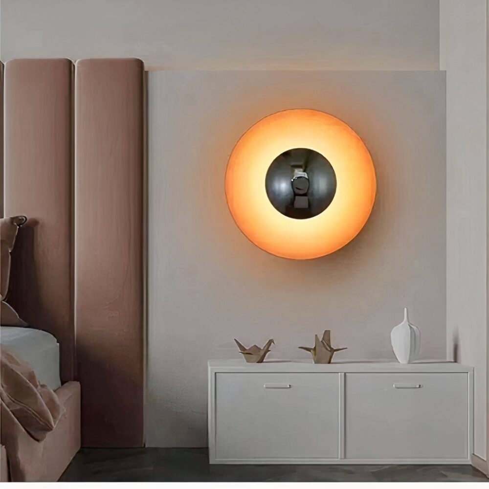in a bedroom with a pink velvet headboard, we see a round vintage-style orange wall light