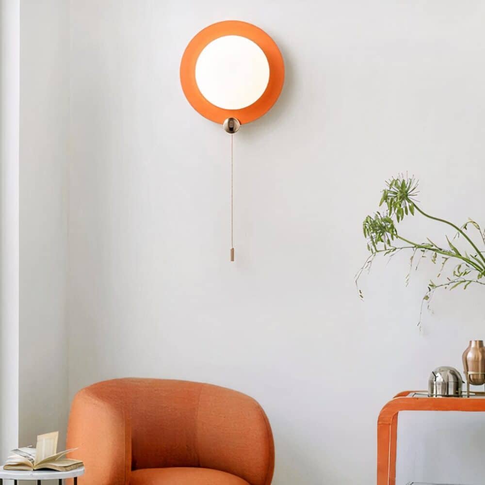 in a living room with gray walls, a modern, round orange wall lamp is mounted on the wall