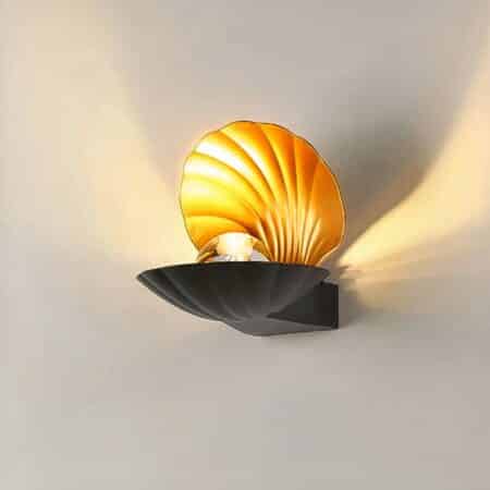 on a light gray background, a black seashell-shaped wall light is lit