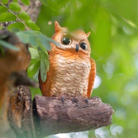 a realistic owl-shaped wall sconce can be seen in a tree