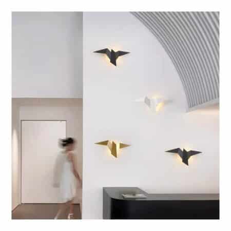we see a white living room with several black, white and gold bird-shaped metal wall sconces on the wall