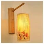 on a beige wall, we see a Japanese wall lamp suspended from bamboo