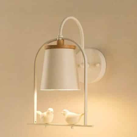on a beige wall, we see a minimalist wall sconce with perched birds