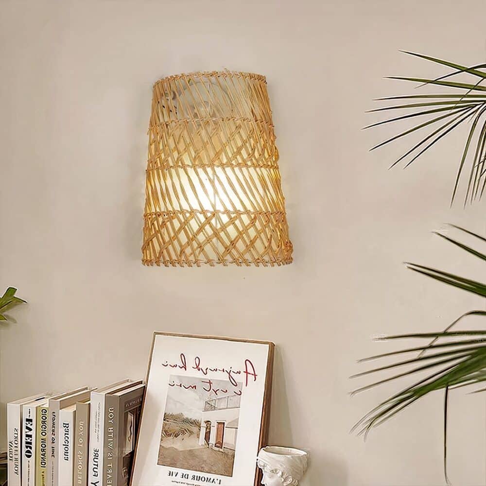 Wicker basket-style wall light hanging on the wall above a piece of furniture with a stack of books on it.
