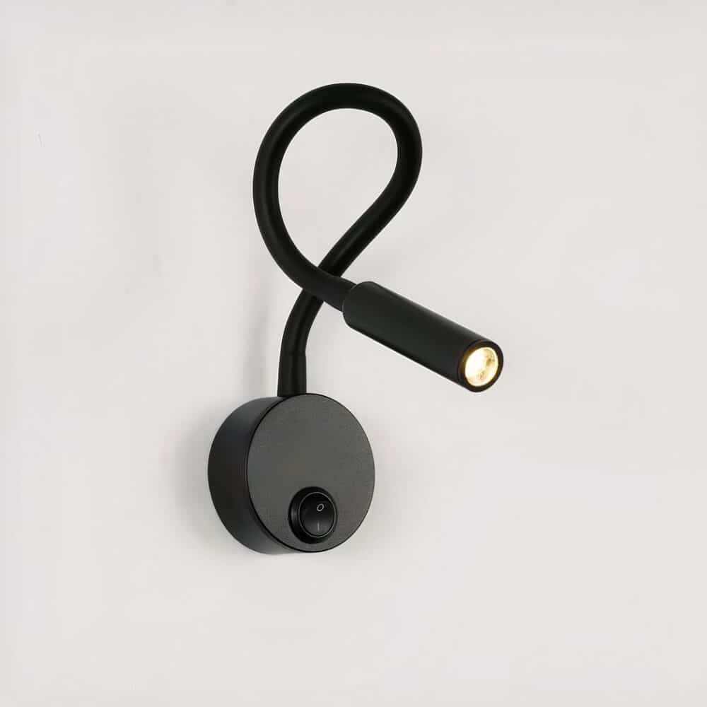Black wall-mounted reading light, round base with switch, flexible stem and lit LED light head.
