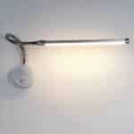 Grey wall-mounted reading light with round base and switch, flexible stem and long light head. On a white background, with the reading light as the only light.